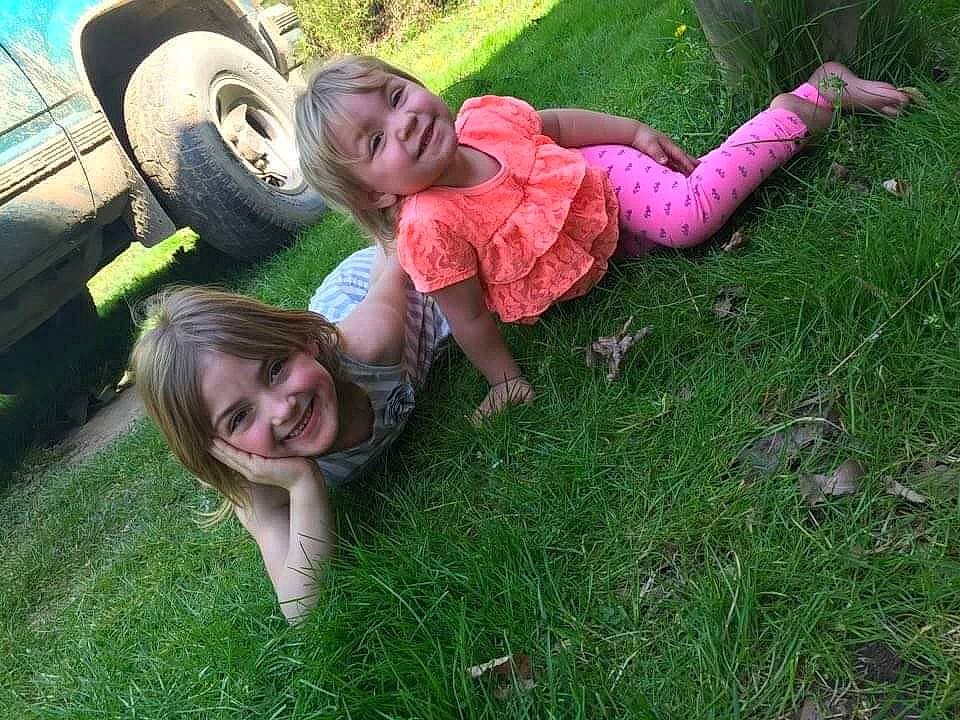 Kaelynn is registered to the contest to win money with this photo: automotive_tire, car, face, fender, fun, grass, grassland, green, happy, joy, leg, leisure, people_in_nature, person, plant, shorts, smile, sneakers, tire, tread