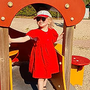 Anna a rejoint le concours — aidez-le/la à gagner de superbes lots ! casual_clothing, child, daytime, footwear, girl, happy, hat, nature, outdoor, person, play, playground, red_dress, sand, slide, smiling, summer, sunglasses, sunny, tree