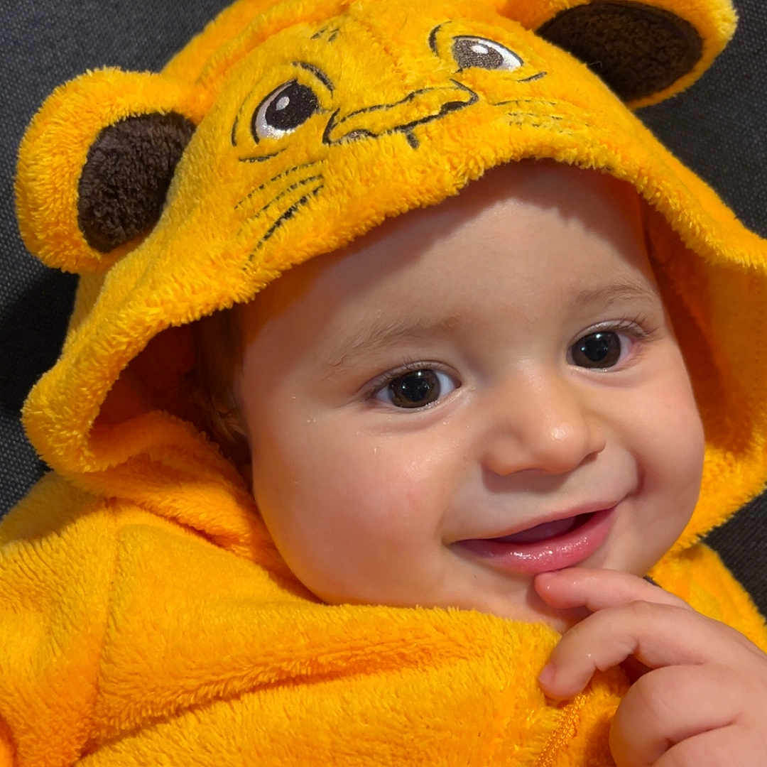 Kleos a rejoint le concours — aidez-le/la à gagner de superbes lots ! animal_ears, baby, child, clothing, costume, cozy, cute, face, finger, fuzzy_texture, hand, happy, hood, indoor, infant, lion_face, portrait, smiling, soft, yellow_costume
