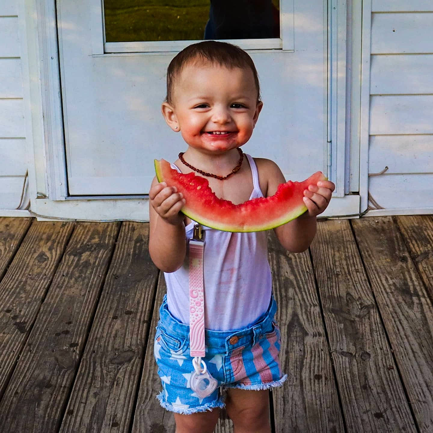 Finley is registered to the contest to win money with this photo: arm, baby, baby_toddler_clothing, child, clothing, door, face, finger, food, fruit, happy, joy, mouth, person, plant, shoulder, sleeve, smile, thumb, toddler