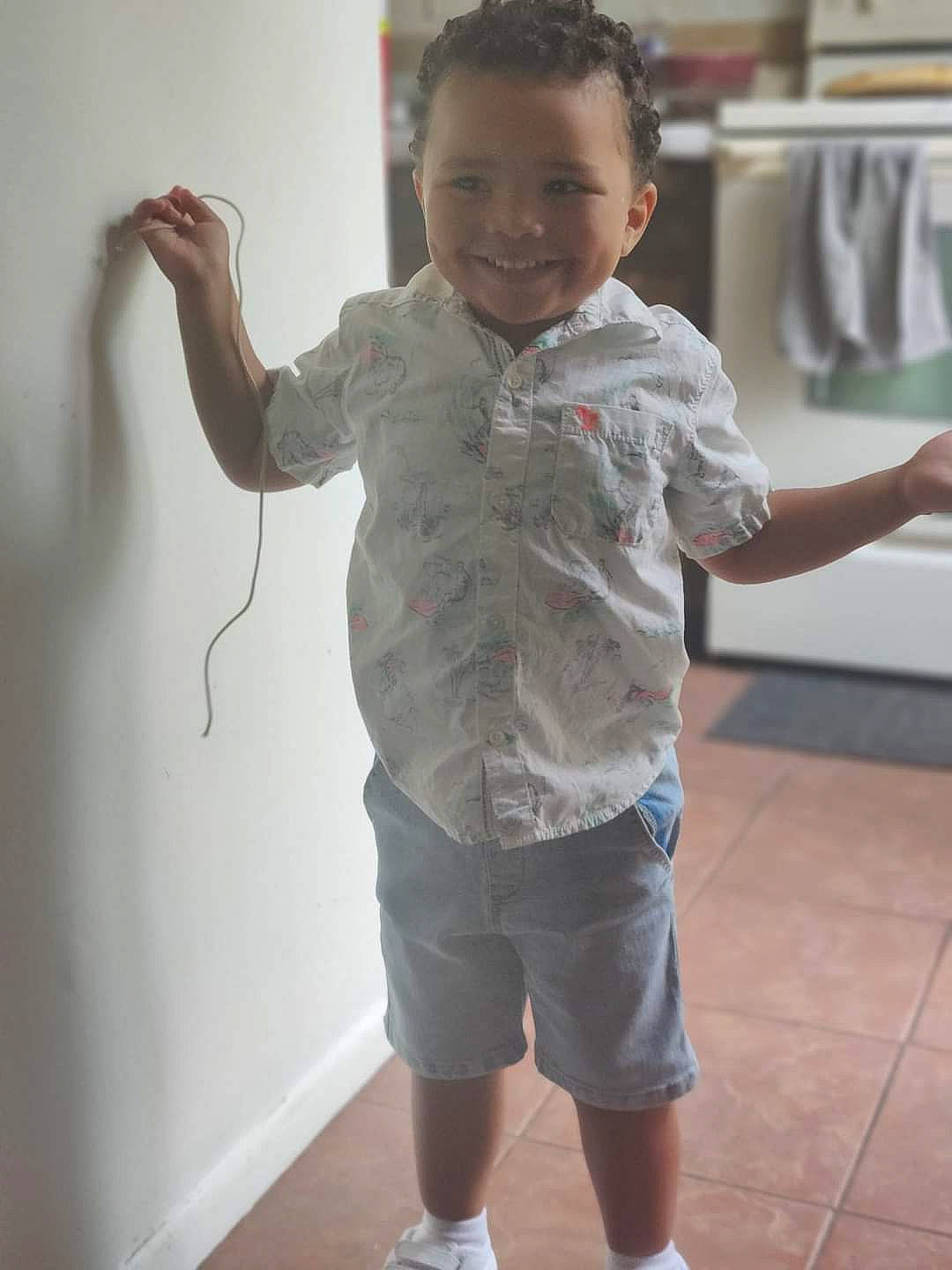 Jonah is registered to the contest to win money with this photo: active_shorts, bermuda_shorts, child, finger, flooring, fun, gesture, happy, joint, joy, organ, person, shorts, shoulder, sleeve, smile, standing, t_shirt, thumb, toddler