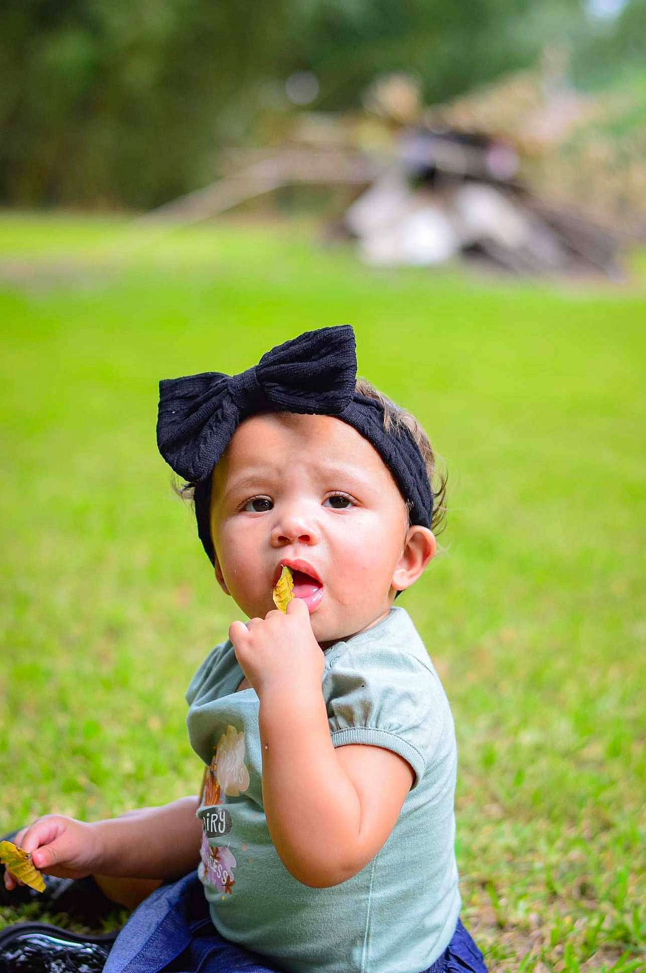 Londynn is registered to the contest to win money with this photo: baby, cap, child, fun, garden, grass, grassland, happy, hat, headwear, landscape, lawn, leisure, people_in_nature, person, plant, recreation, sitting, sun_hat, toddler