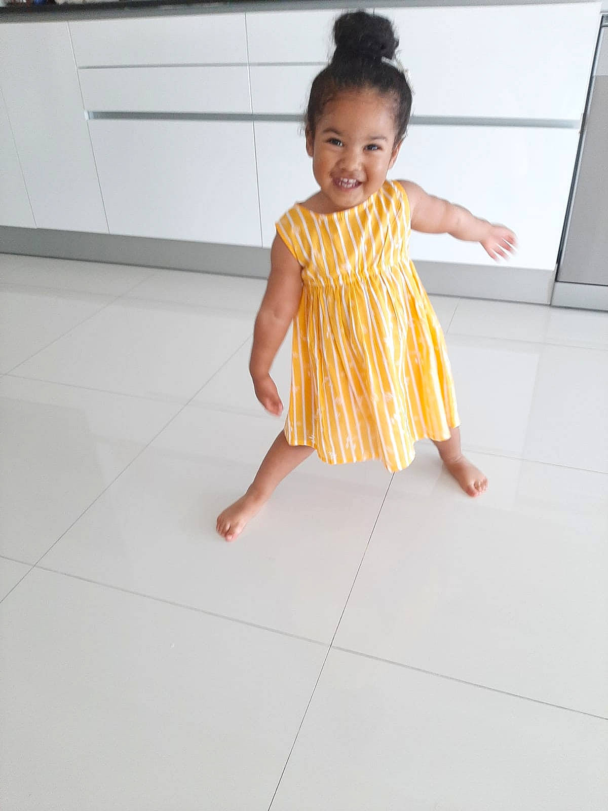 Eléa a rejoint le concours — aidez-le/la à gagner de superbes lots ! arm, baby_toddler_clothing, barefoot, day_dress, dress, face, floor, flooring, foot, hair, happy, joy, neck, one_piece_garment, person, shoulder, skin, sleeve, smile, thigh