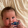 baby, infant, child, cute, cheeks, hair, phone_case, cartoon, stitch, blanket, white, lying_down, hands, face, eyes, playing, indoor, soft_light, skin, adorable