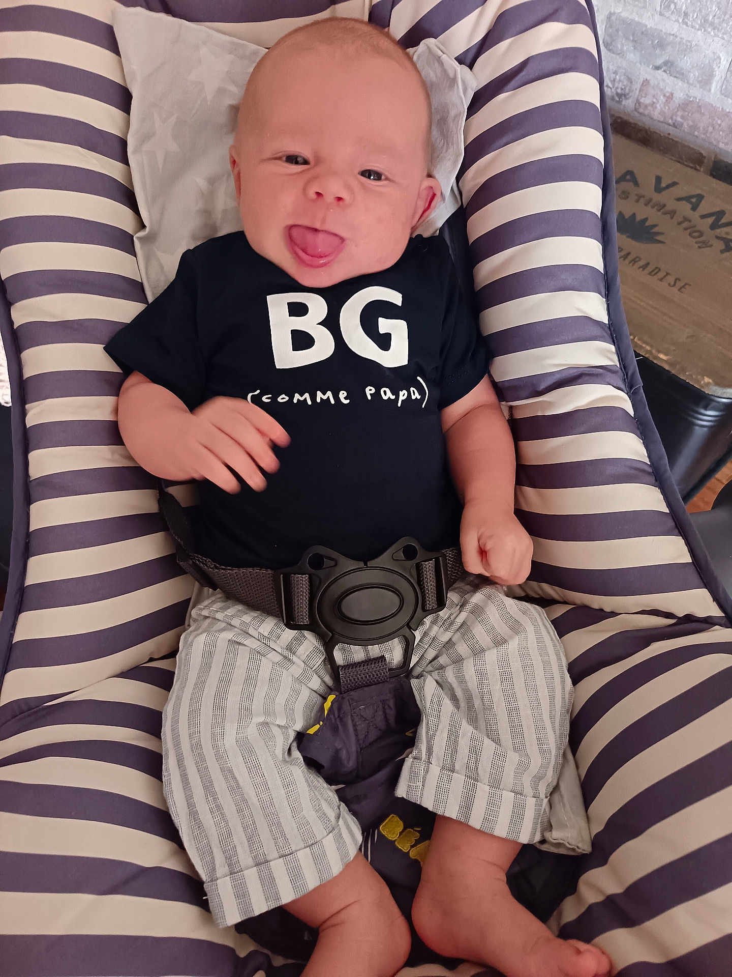 Eliott a rejoint le concours — aidez-le/la à gagner de superbes lots ! baby, infant, child, smiling, tongue_out, striped_clothing, black_shirt, striped_pants, baby_seat, cushion, indoor, playful, happy, person, seatbelt, comfortable, cute, head, face, feet