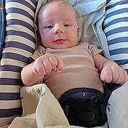 Eliott participe au concours pour gagner de l'argent avec cette photo : baby, child, infant, cushion, striped, blanket, clothing, seat, face, hands, comfort, indoor, cute, young, portrait, person, soft, resting, fist, expression