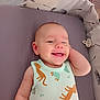 Eliott participe au concours pour gagner de l'argent avec cette photo : animal_print, baby, cheerful, child, clothing, cute, face, hand, happy, indoors, infant, lying_down, onesie, pacifier, playpen, purple_mattress, relaxed, smiling, soft_fabric, toddler