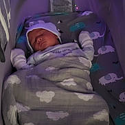 Greyson is registered to the contest to win money with this photo: baby, newborn, sleeping, blanket, crib, hat, bedding, elephant_pattern, cloud_pattern, infant, cozy, child, nursery, resting, indoors, soft_lighting, cute, wrapped, peaceful, bed