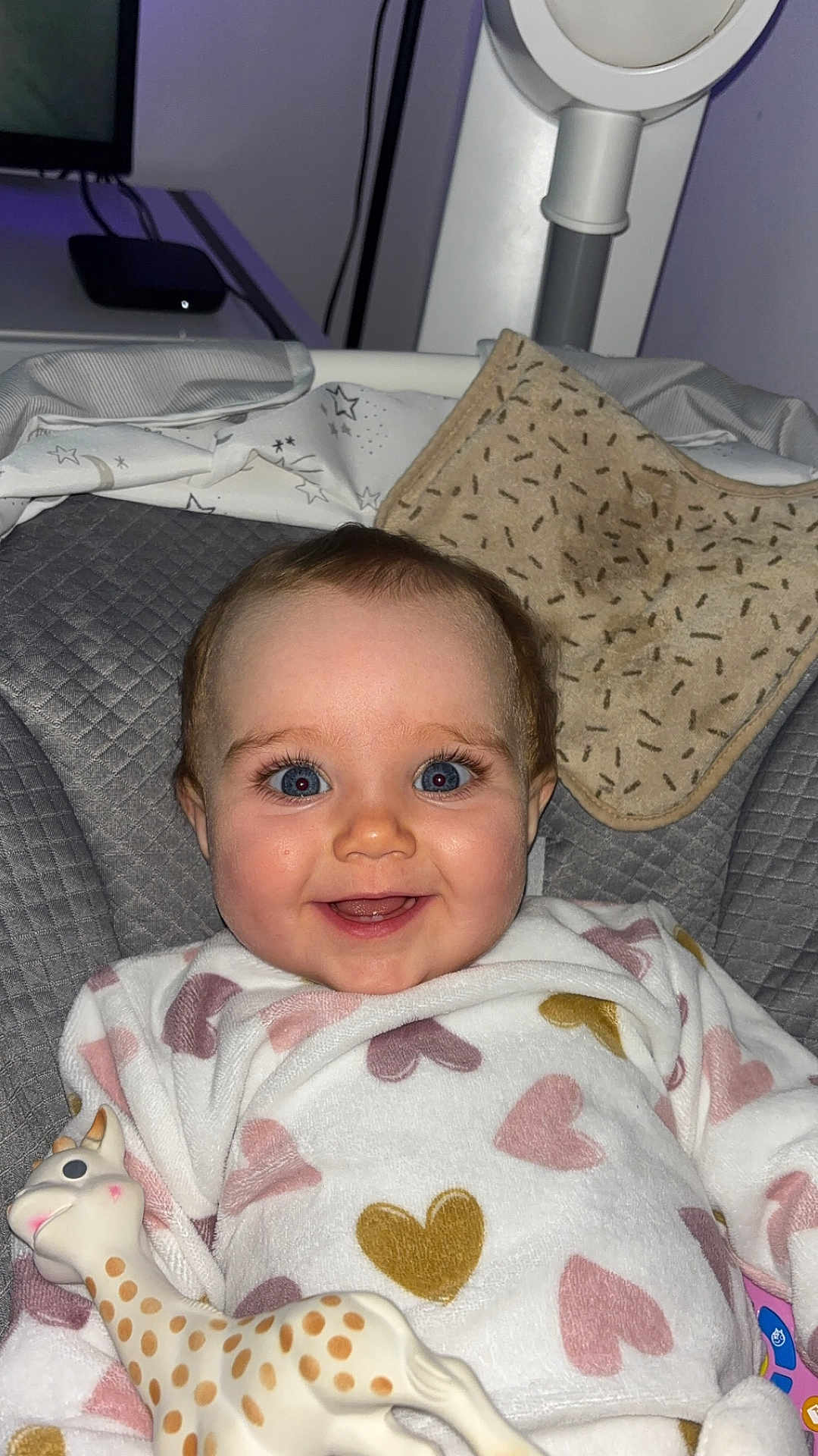 Annalia a rejoint le concours — aidez-le/la à gagner de superbes lots ! baby, baby_clothing, bib, blue_eyes, chair, child, cozy, cushion, cute, face, giraffe_toy, happy, heart_pattern, indoor, infant, onesie, person, portrait, smiling, toy