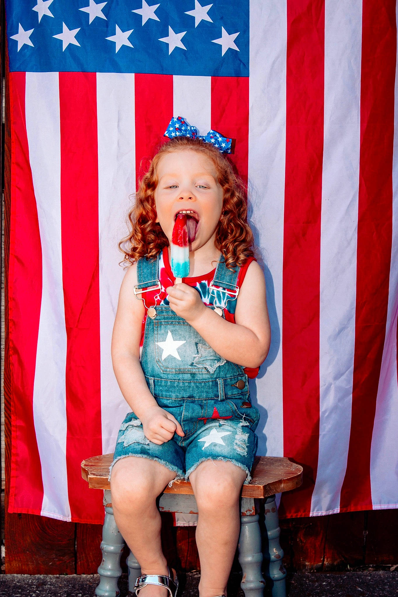 Kinsley is registered to the contest to win money with this photo: baby_toddler_clothing, blue, costume_accessory, denim, eye, flag, flag_day_usa, flag_of_the_united_states, hair_accessory, headband, headpiece, jeans, leg, mouth, nose, party_supply, person, red, sitting, textile