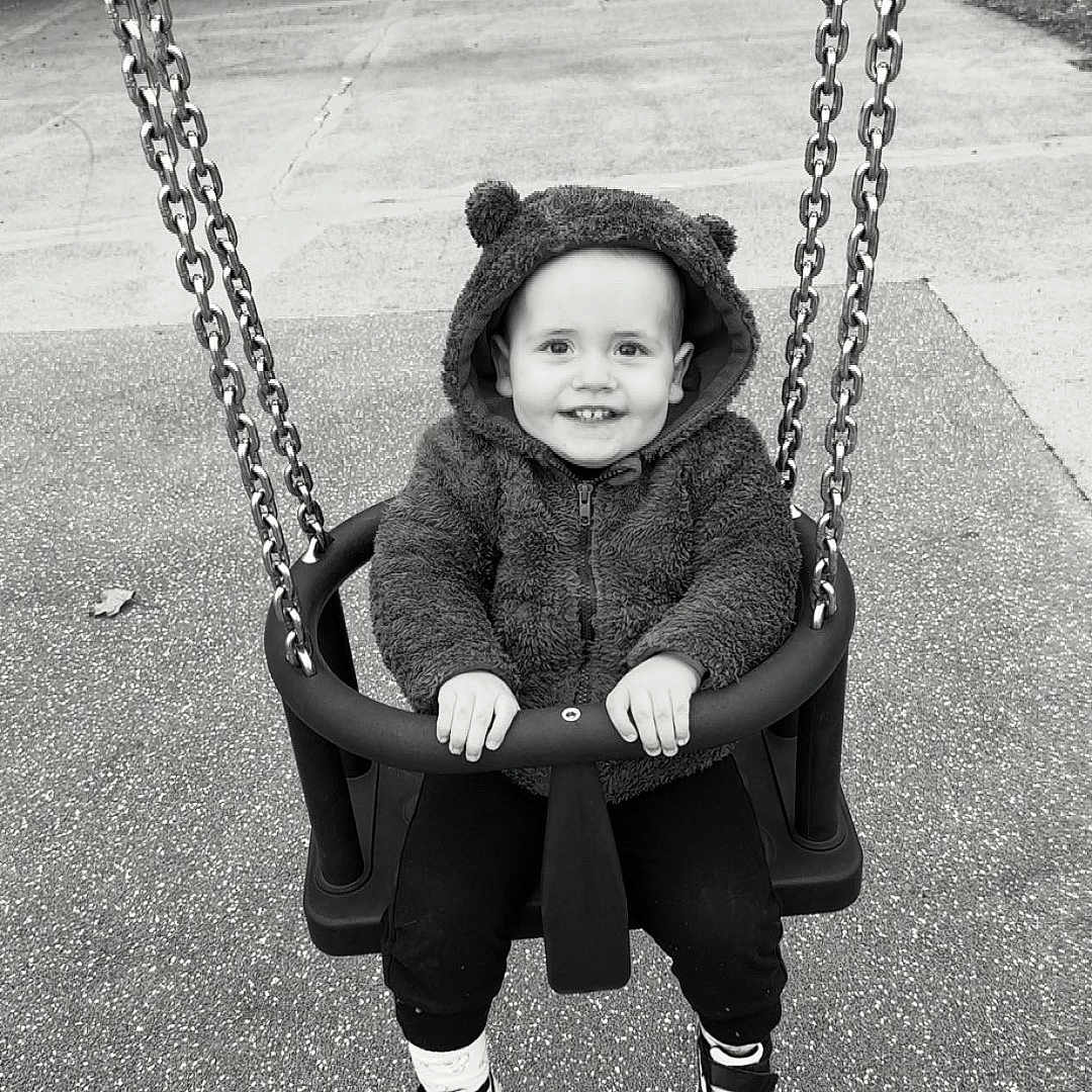 Owen participe au concours pour gagner de l'argent avec cette photo : baby_swing, black_and_white, casual, chains, child, clothing, cute, fun, happy, hoodie, outdoor, park, person, playground, seat, sitting, smile, sneakers, swing, toddler