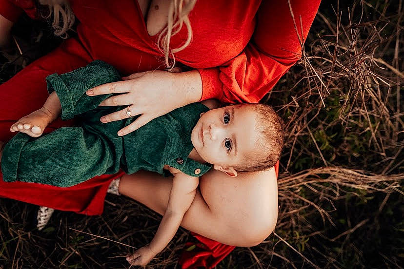 Atlas is registered to the contest to win money with this photo: abdomen, baby, comfort, eye, finger, flash_photography, grass, hand, happy, human_body, human_leg, leg, person, plant, red, skin, thigh, toddler, tree, trunk