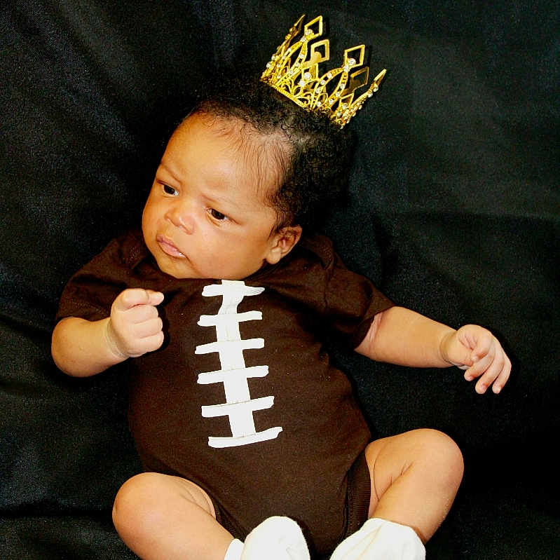 Hasan is registered to the contest to win money with this photo: accessories, baby, bodypart, clothing, costume, crown, face, finger, hand, head, hosiery, jewelry, newborn, person, photography, portrait, sitting, sock, t_shirt, tiara