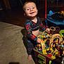 baby, bead_maze, carpet, child, colorful, cute, furniture, happy, indoor, living_room, pajamas, person, play, shadow, smiling, spiderman, toddler, toy, wooden_floor, wooden_toy