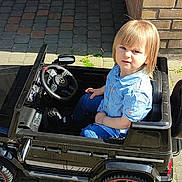 Kinslay a rejoint le concours — aidez-le/la à gagner de superbes lots ! child, toddler, toy_car, steering_wheel, mercedes_logo, denim_shirt, blue_jeans, brick_wall, paved_driveway, sunlight, shadow, outdoor, pavement, wheel, portrait, sitting, candid, sidewalk, smartphone_screenshot, vehicle_toy