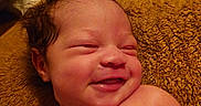 Aspen is registered to the contest to win money with this photo: baby, newborn, smiling, curly_hair, skin, blanket, texture, lying_down, infant, happy, child, portrait, indoors, warm_lighting, cute, closeup, sleepy, relaxed, soft, person