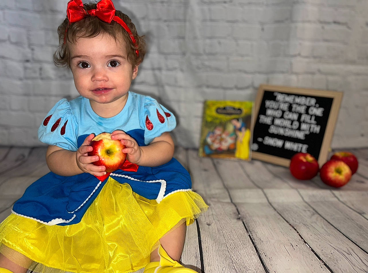 Fallon is registered to the contest to win money with this photo: baby_toddler_clothing, baby_toys, child, costume, dress, flooring, fun, happy, orange, pattern, person, play, room, sitting, sleeve, stuffed_toy, t_shirt, toddler, toy, vacation