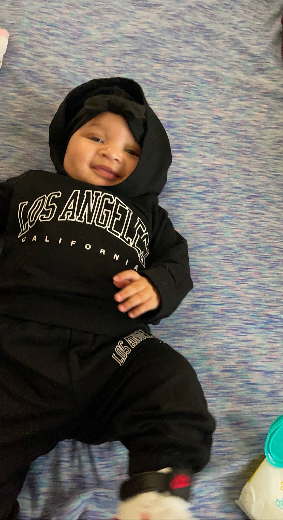 Lillyann is registered to the contest to win money with this photo: baby, baby_products, baby_toddler_clothing, beanie, cap, child, face, fashion_accessory, fun, happy, headwear, hood, hoodie, knit_cap, person, personal_protective_equipment, sitting, sleeve, smile, t_shirt