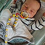 Augustin participe au concours pour gagner de l'argent avec cette photo : baby, sleeping, pacifier, blanket, crib, striped_clothing, infant, cute, child, resting, bed, face, person, indoors, soft_toys, baby_accessories, warm, comfort, peaceful, nap