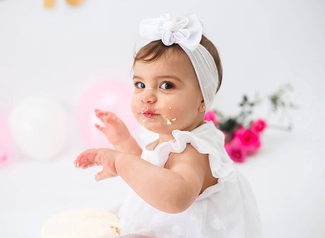 Anna participe au concours pour gagner de l'argent avec cette photo : baby, baby_toddler_clothing, child, dress, eyelash, face, finger, flash_photography, gesture, happy, headband, headgear, headpiece, lip, person, petal, pink, skin, smile, textile
