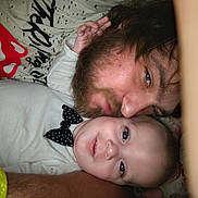 Johnny joined the competition — help win amazing prizes! baby, man, beard, face, smile, close_up, indoor, person, child, casual_clothing, graphic_tee, polka_dot, bow_tie, hand, affection, selfie, lying_down, skin, blue_eyes, tender_moment