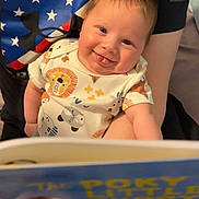 Colton is registered to the contest to win money with this photo: baby, bed, bodypart, clothing, couch, crib, dress, face, finger, furniture, hand, head, infantbed, newborn, person, photography, portrait, reading, sitting, t_shirt