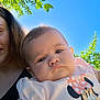 Bella is registered to the contest to win money with this photo: baby, child, person, face, outdoor, blue_sky, green_leaves, sunlight, pout, clothing, cartoon_character, minnie_mouse, shirt, adult, holding, nature, portrait, summer, daylight, selfie