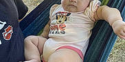 Bella joined the competition — help win amazing prizes! baby, infant, child, person, onesie, clothing, minnie_mouse, hammock, outdoor, grass, sunlight, adult, lap, resting, cute, chubby, legs, feet, face, portrait