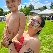 Nathaniel Truncer is registered to the contest to win money with this photo: child, adult, shirtless, tattoo, face_paint, glasses, outdoor, green_grass, blue_sky, sunny, holding, smile, happy, person, family, playful, portrait, daytime, nature, people