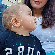 Dustin is registered to the contest to win money with this photo: baby, woman, outdoor, sparkle_filter, shirt, text_on_clothing, lip_piercing, curly_hair, portrait, child, casual_clothing, nature_background, tree, daylight, face, smile, seated, person, blue_sky, candid