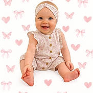 Emma joined the competition — help win amazing prizes! baby, smiling, sitting, headband, onesie, cute, happy, infant, pink, pattern, background, heart, butterfly, bow, child, portrait, skin, feet, hand, clothing