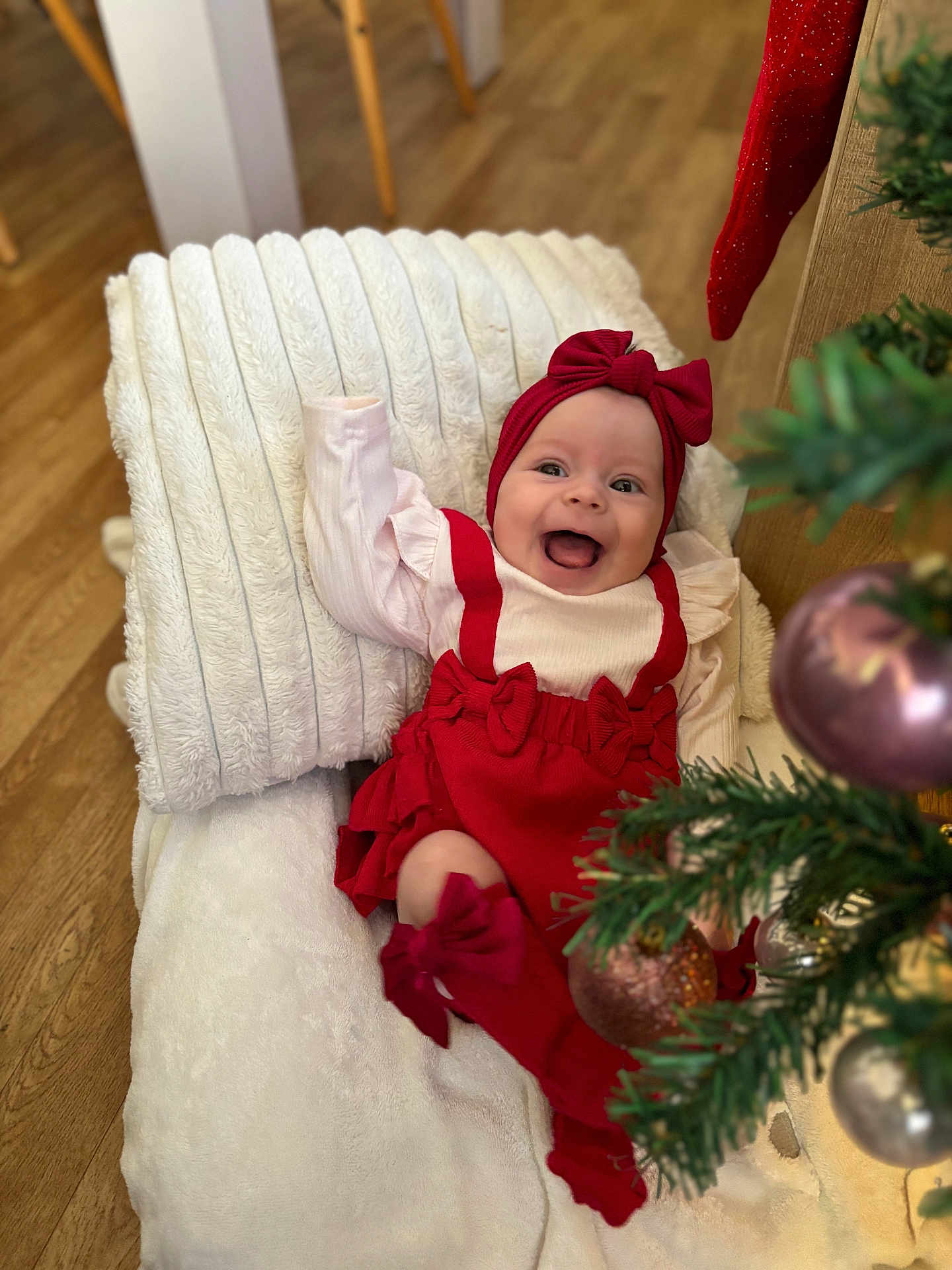 Soëlya participe au concours pour gagner de l'argent avec cette photo : baby, infant, smiling, red_clothing, headband, blanket, christmas_tree, ornaments, holiday, indoor, wood_floor, cushion, happy, cute, festive, decor, person, toddler, celebration, home