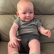 Teddie joined the competition — help win amazing prizes! baby, infant, smiling, sitting, shoe, sneaker, clothing, grey_shirt, shorts, leather_couch, cute, child, person, footwear, happy, indoors, young_child, casual, comfortable, portrait