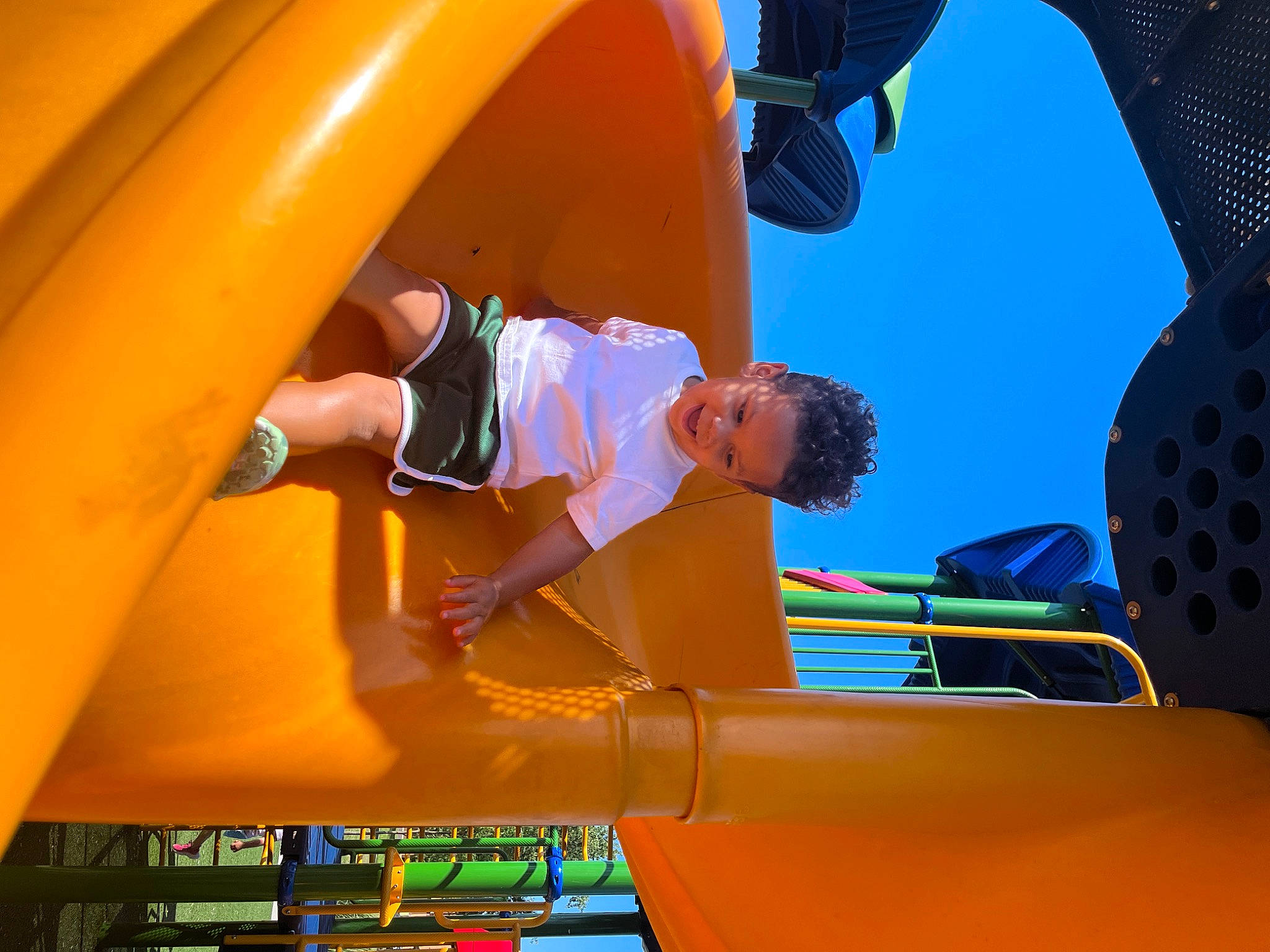 Emerson is registered to the contest to win money with this photo: automotive_exterior, child, chute, city, electric_blue, fun, joy, leisure, motor_vehicle, outdoor_play_equipment, person, play, playground, recreation, shorts, sky, smile, t_shirt, toddler, yellow