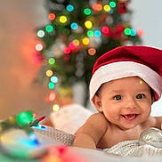 Shriyan Rakshit joined the competition — help win amazing prizes! baby, smiling, santa_hat, christmas_lights, christmas_tree, holiday, festive, infant, blanket, cute, happy, indoors, decorations, portrait, child, celebration, colorful, warm, holiday_spirit, tongue_out