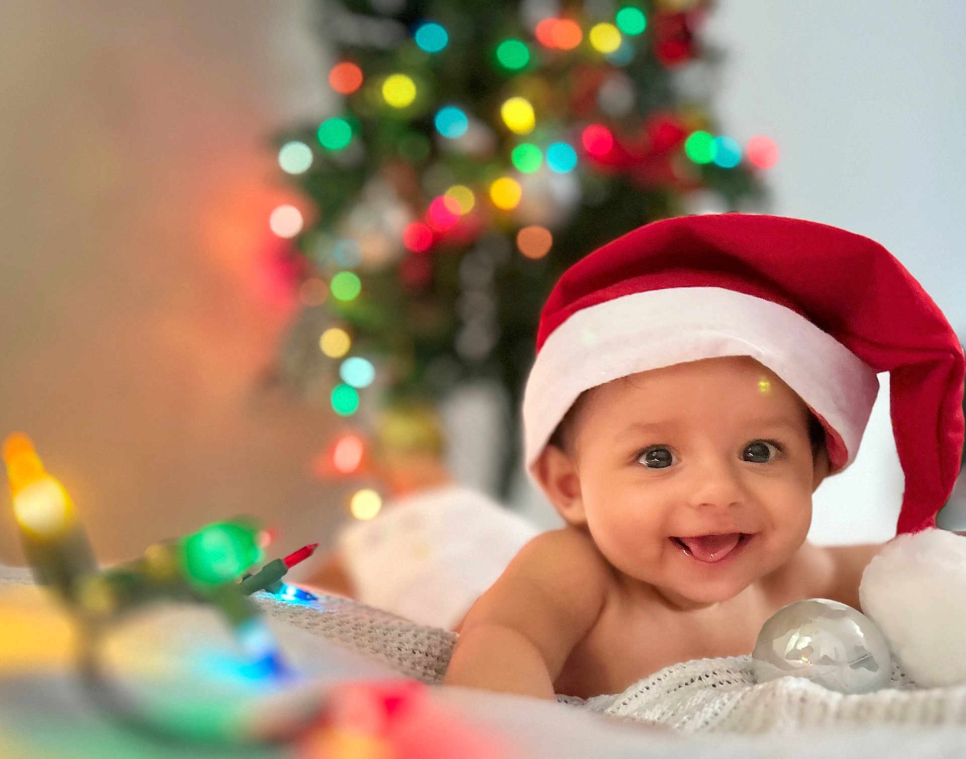 Shriyan Rakshit joined the competition — help win amazing prizes! baby, smiling, santa_hat, christmas_lights, christmas_tree, holiday, festive, infant, blanket, cute, happy, indoors, decorations, portrait, child, celebration, colorful, warm, holiday_spirit, tongue_out