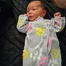 baby, newborn, infant, onesie, floral_pattern, sleepwear, hand, bed, quilt, resting, cozy, soft, cute, child, person, skin, face, sleep, indoors, comfort