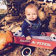 Tristan joined the competition — help win amazing prizes! baby, child, wagon, radio_flyer, pumpkin, firewood, overalls, blanket, outdoor, fall, autumn, cute, portrait, smiling, person, blue_eyes, nature, daylight, wood, seasonal