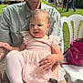 baby, child, adult, sunglasses, pink_dress, leggings, outdoor, garden, people, chair, handbag, grass, string_lights, casual, event, reflection, person, nature, summer, family