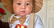 Andres joined the competition — help win amazing prizes! baby, child, hat, bow_tie, shirt, lion_print, suspenders, indoor, face, portrait, cute, chubby_cheeks, expression, person, infant, clothing, light, skin, hand, background