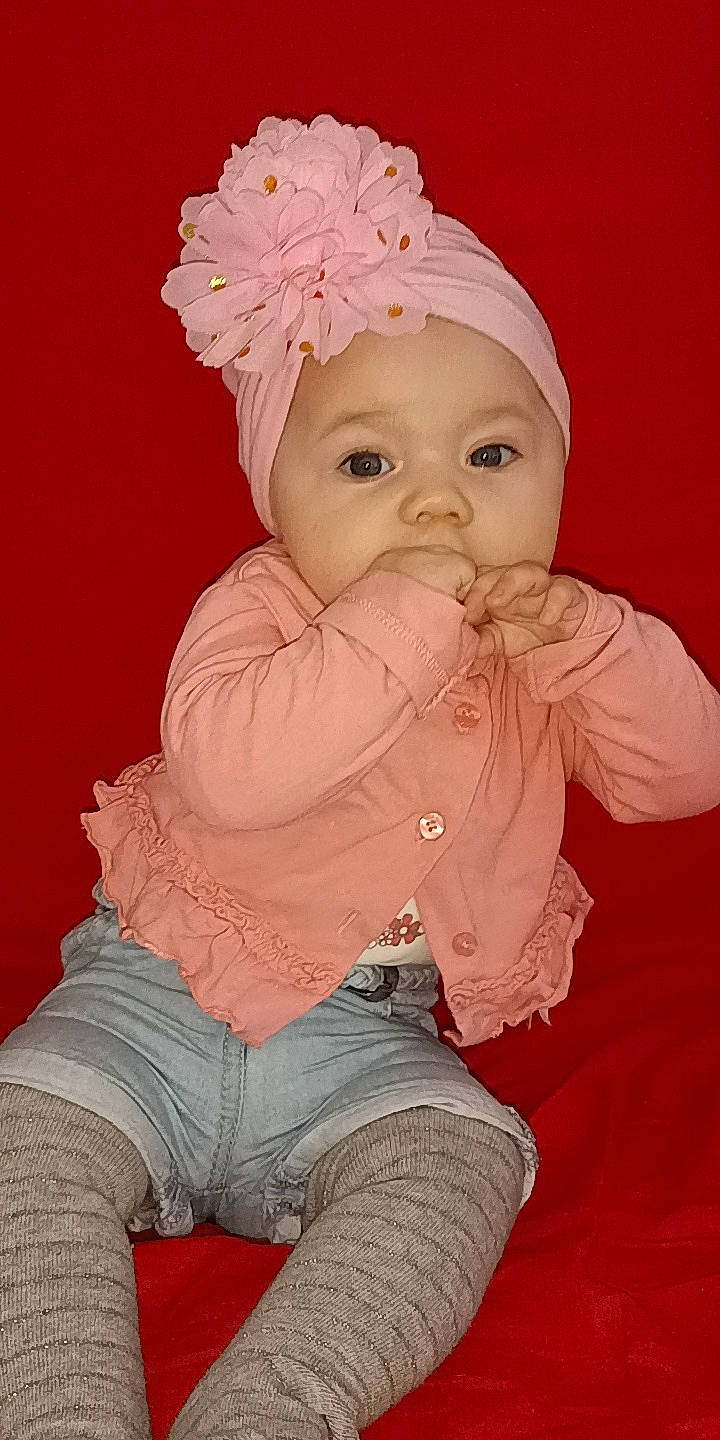 Kenza participe au concours pour gagner de l'argent avec cette photo : baby, baby_toddler_clothing, cap, cheek, child, costume_hat, eye, hand, head, headgear, headwear, human_body, lip, magenta, peach, person, pink, sitting, skin, sleeve