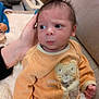 Sohan a rejoint le concours — aidez-le/la à gagner de superbes lots ! baby, newborn, infant, onesie, orange_clothing, face, eyes, side_eye, blanket, sofa, hand, pacifier, cute, portrait, indoor, fur_texture, hair, young_child, human, expression