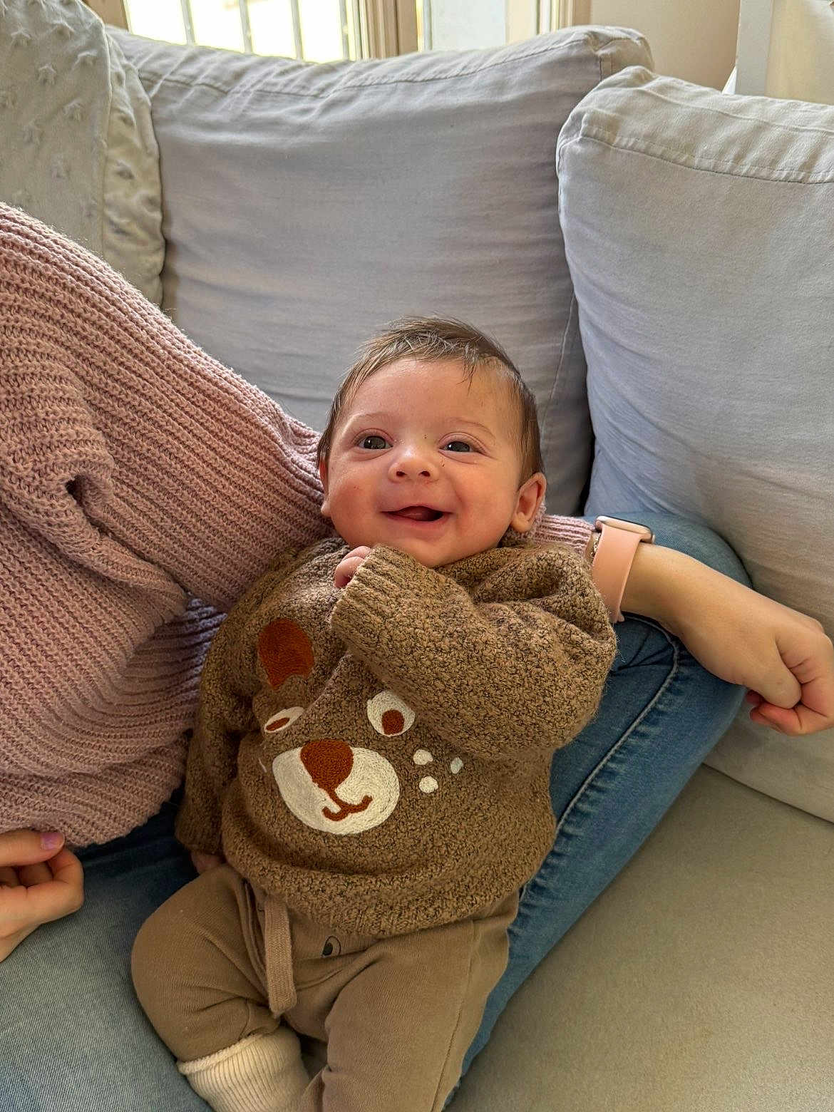 Sohan a rejoint le concours — aidez-le/la à gagner de superbes lots ! baby, infant, smile, bear_sweater, knit_sweater, sofa, couch, cushion, arm, smartwatch, jeans, cozy, indoor, portrait, cute, happy, sitting, family_member, hand, soft_lighting