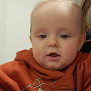 Nolan participe au concours pour gagner de l'argent avec cette photo : baby, child, hoodie, orange_clothing, toy_story, woody, indoor, brick_ceiling, hand, face, person, curious, close_up, young_child, casual_clothing, portrait, expression, candid, human, indoor_lighting
