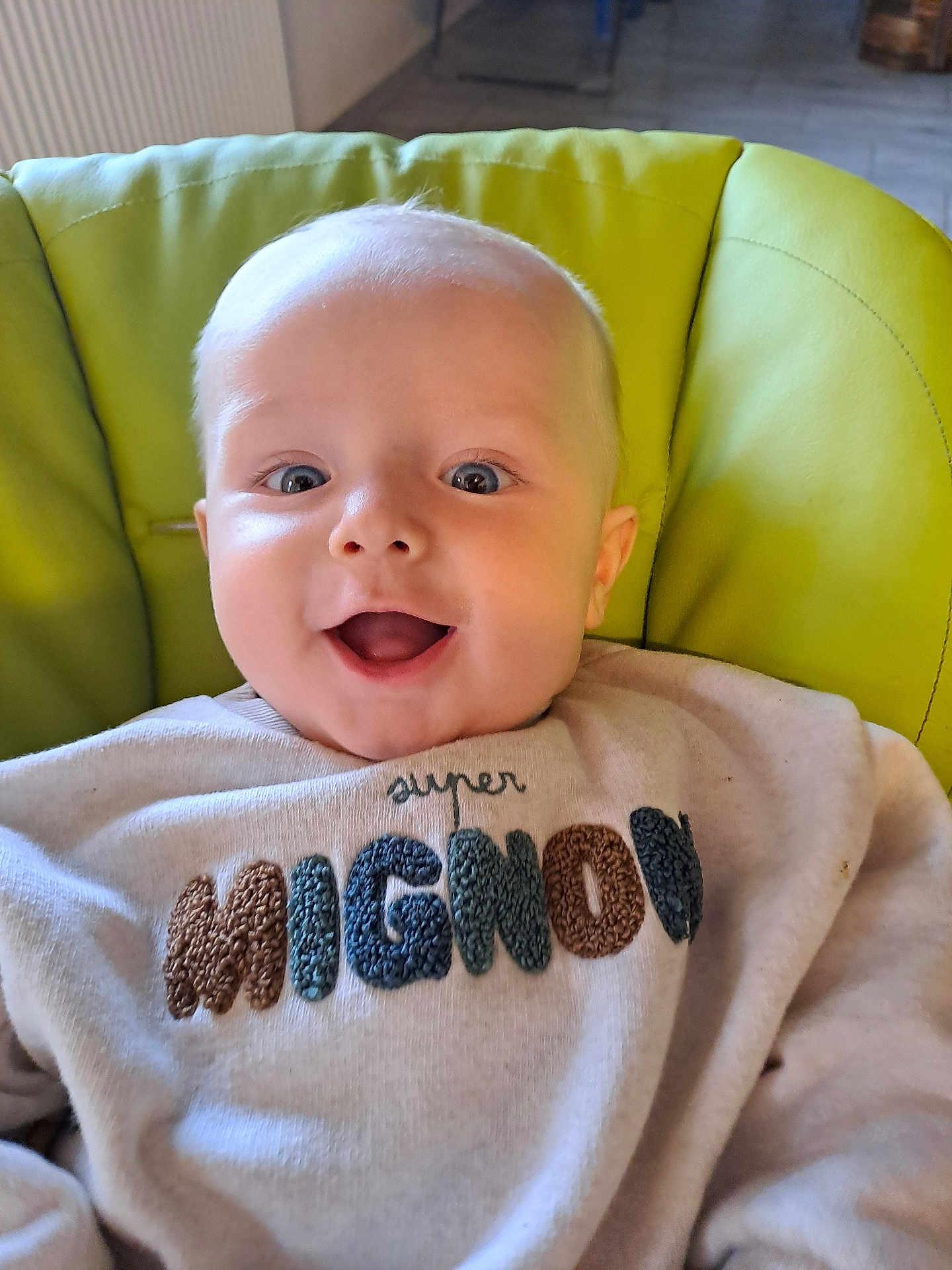 Nolan participe au concours pour gagner de l'argent avec cette photo : baby, smiling, child, face, sweater, clothing, indoor, seat, chair, happy, cute, portrait, young, infant, human, person, light, expression, comfort, cozy