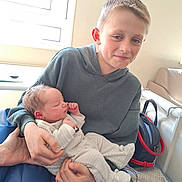 Lucas a rejoint le concours — aidez-le/la à gagner de superbes lots ! child, baby, newborn, boy, sibling, indoor, window, hoodie, smile, holding, family, bed, chair, backpack, casual, person, clothing, light, peaceful, portrait