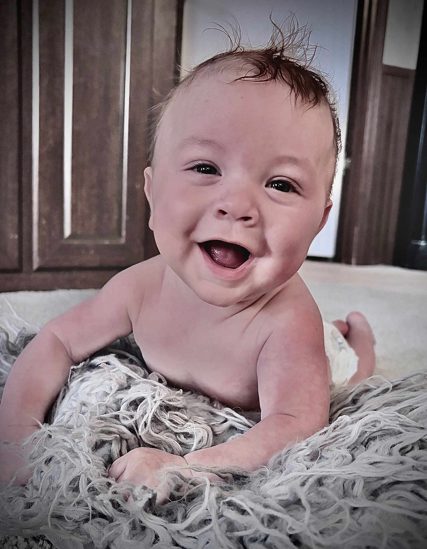 Creed is registered to the contest to win money with this photo: baby, infant, smiling, happy, tongue, face, eyes, hair_spikes, diaper, blanket, textured_blanket, floor, wooden_cabinet, indoor, portrait, closeup, skin, crawling, playful, adorable