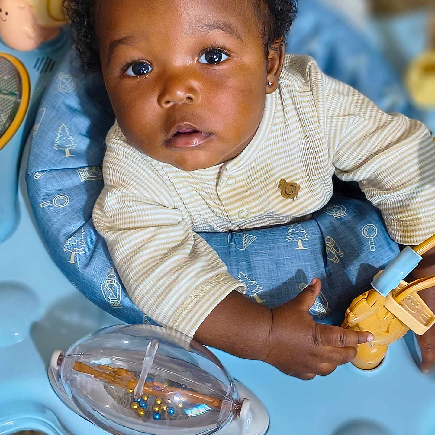 Santavious joined the competition — help win amazing prizes! activity_center, baby, blue, child, closeup, clothing, curious, cute, earring, exploring, expression, face, hand, indoor, infant, playtime, portrait, striped, toy, yellow