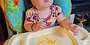 Ember joined the competition — help win amazing prizes! toddler, child, high_chair, pigtails, food, cheese, funny_face, indoor, living_room, laundry_basket, blanket, table, plastic_tray, floor, toy, bracelet, seat_recline, couch, person, hair