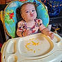 toddler, child, high_chair, pigtails, food, cheese, funny_face, indoor, living_room, laundry_basket, blanket, table, plastic_tray, floor, toy, bracelet, seat_recline, couch, person, hair